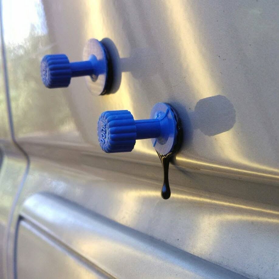 Blue glue-pull tabs attached to a silver vehicle door during paintless dent repair