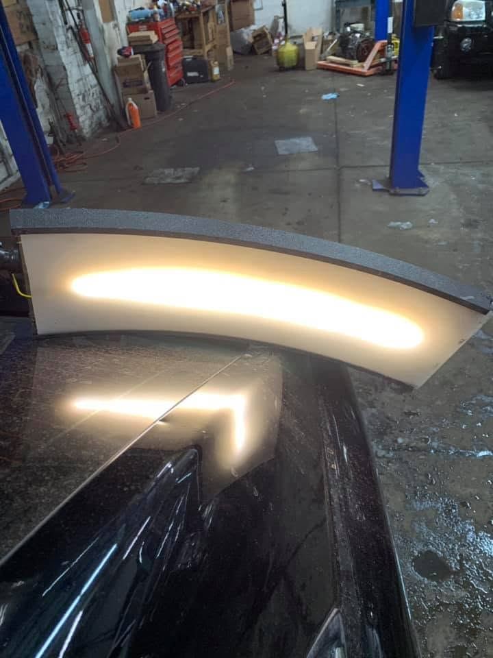 PDR reflection light board positioned over a black vehicle panel to reveal the shape of a dent
