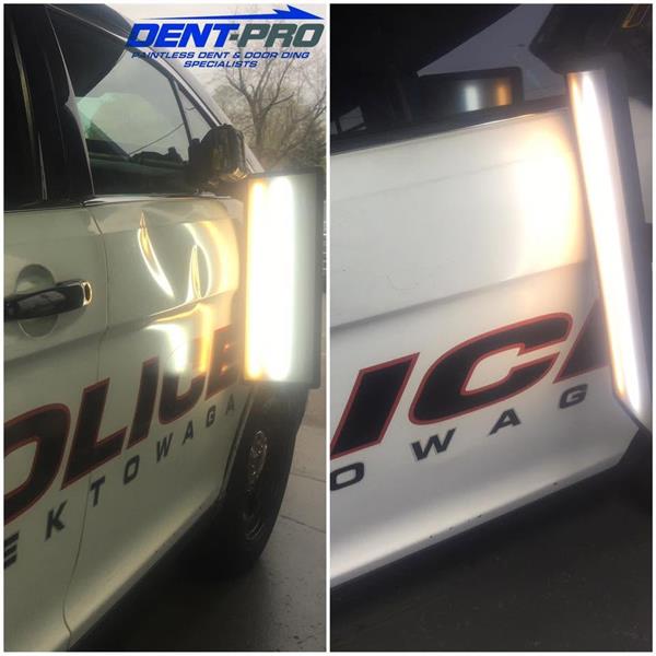Paintless dent repair on a police vehicle door under a PDR light